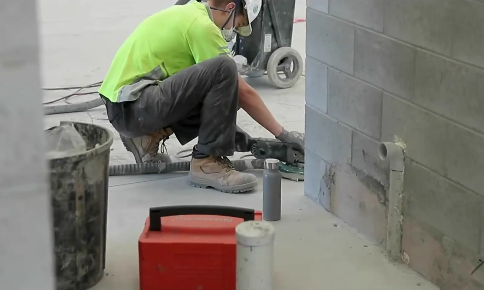 Apex crew member grinding at the base of a wall with dust extraction