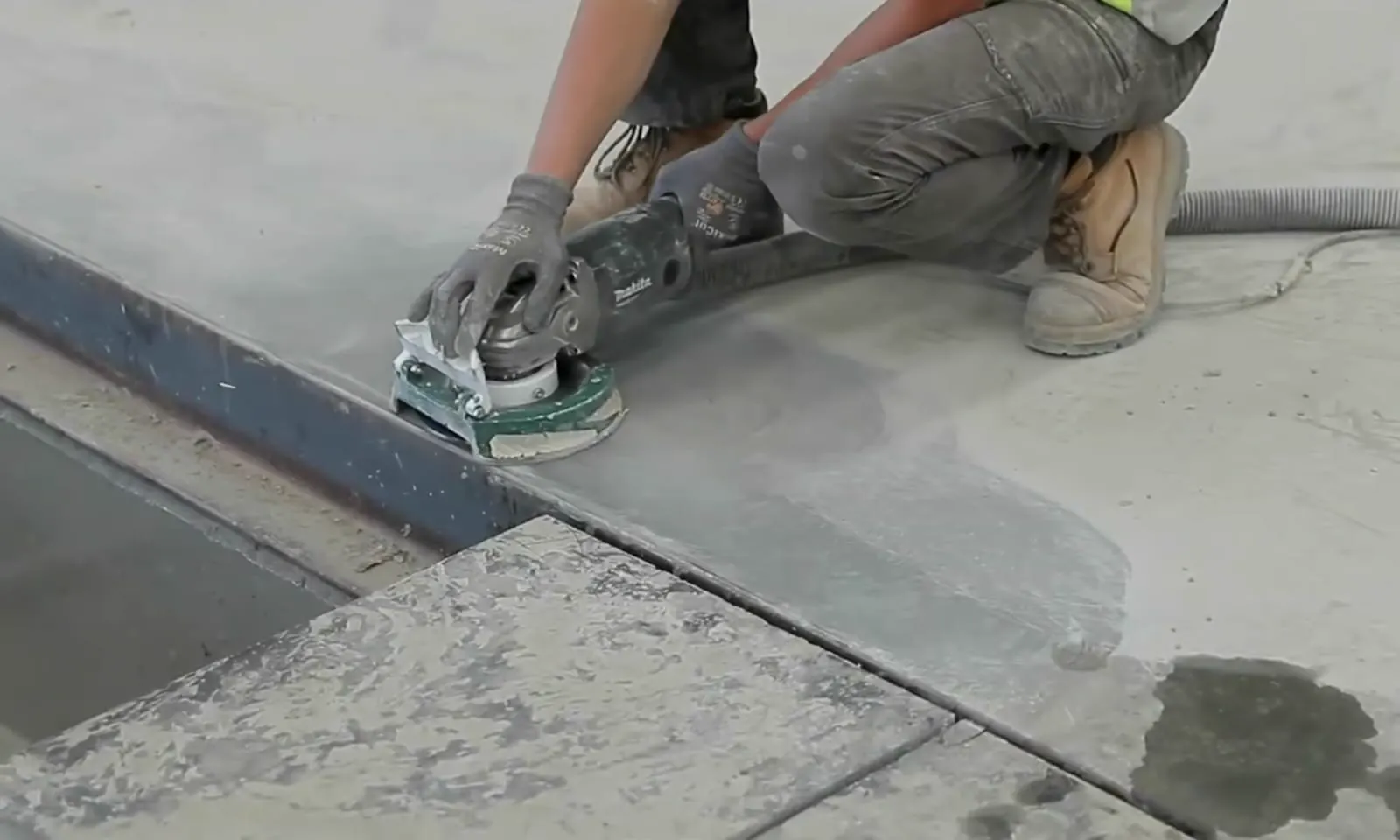 Edge grinding along a slab joint with a shrouded grinder