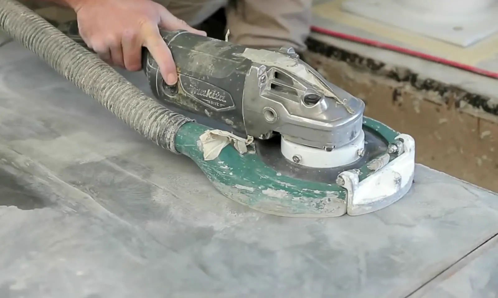 Hand grinder with vacuum shroud removing surface material